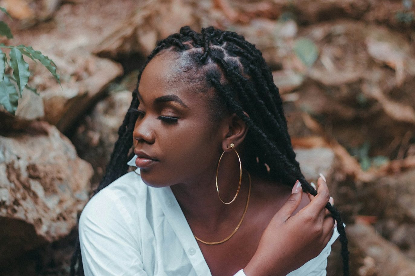 a woman with dreadlocks sitting in front of rocks